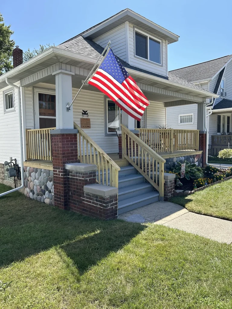 Rebuilt wooden porch with American flag at residential home by Union Properties in Huron, MI