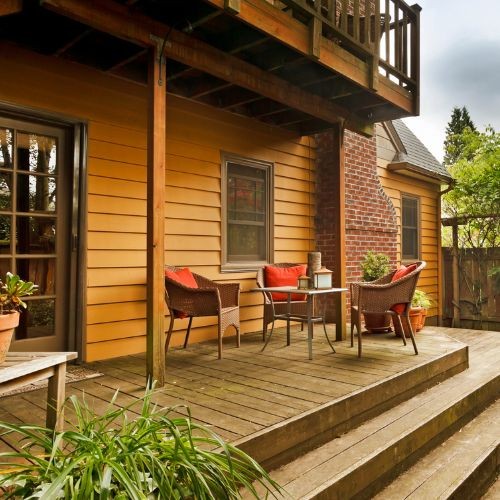 Single level wooden deck with seating area, potted plants, and warm house siding by Union Properties in Michigan