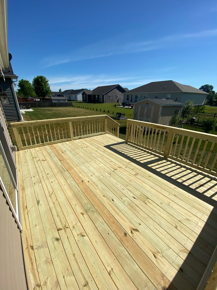 New pressure-treated wood deck with railings overlooking a backyard, deck resurfacing vs replacement in Michigan by Union Properties