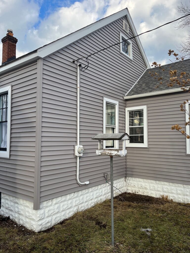 completed home exterior with gray vinyl siding and white trim around windows in Port Huron