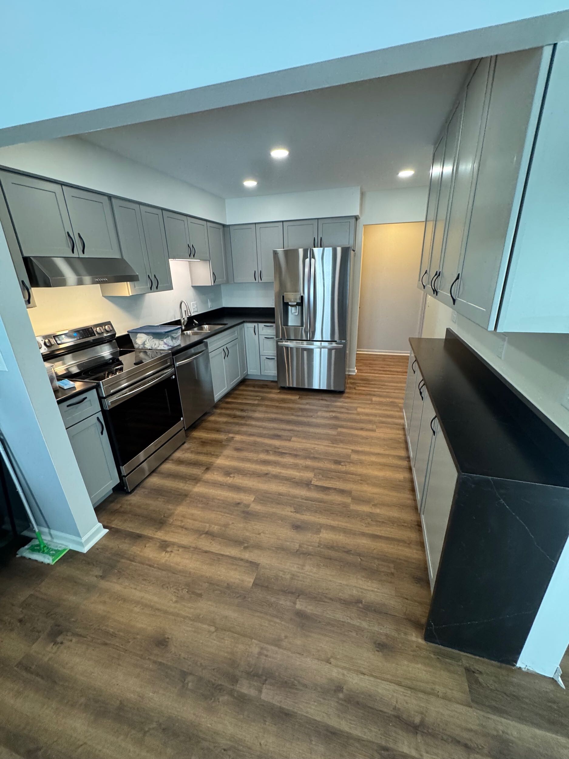 Contemporary kitchen with gray cabinets, black countertops, and stainless steel appliances, highlighting what is a general contractor delivering completed projects in Port Huron