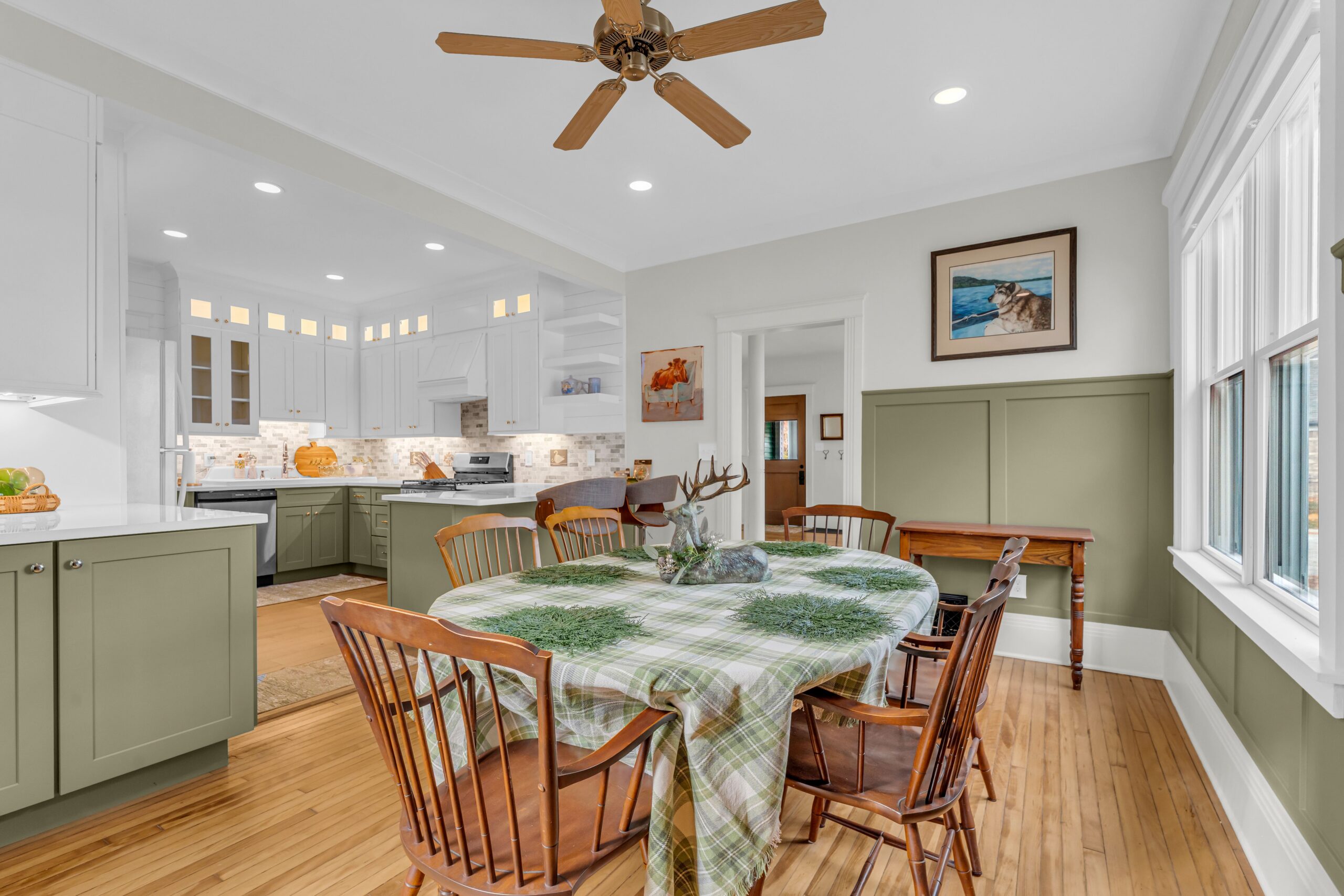 A remodeled kitchen and dining area featuring sage green wainscoting, an open layout, and a classic wooden dining table, showcasing a historic home remodel Port Huron MI by Union Properties.