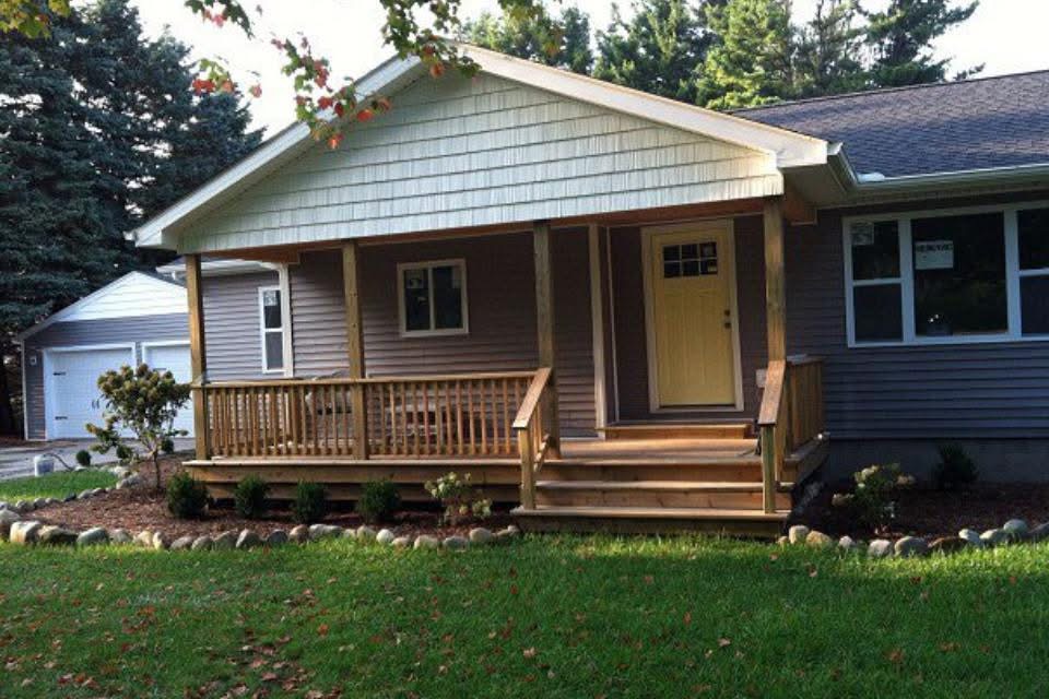 A covered front porch featuring light shakes and horizontal siding built by an expert siding contractor port huron in Port Huron by Union Properties.