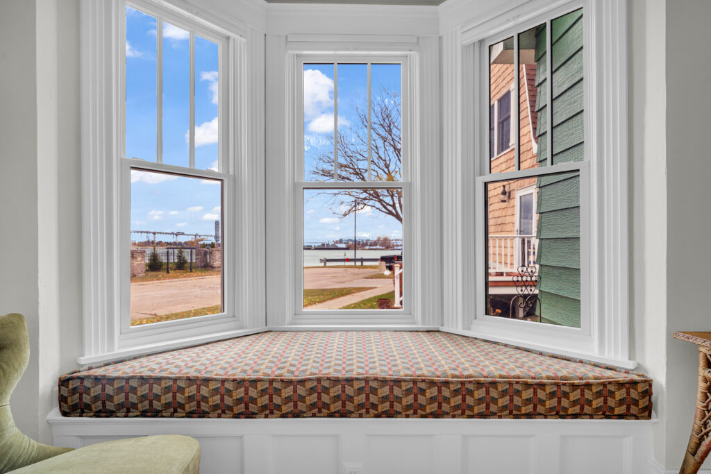 A bright interior bay window nook with custom white trim and a cushioned bench seat showcasing energy-efficient window installation and replacement in Port Huron by Union Properties.